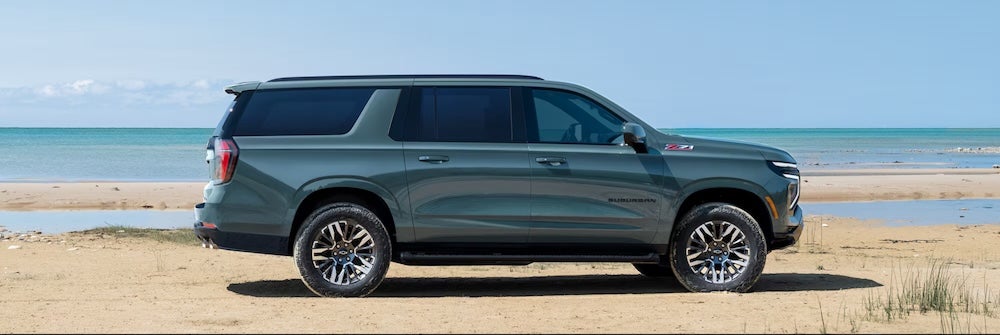 A green 2026 Chevrolet Suburban SUV parked on the beach